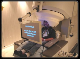 A child reads instructions on a screen while seated with his head surrounded by the MEG's noninvasive magnetic detectors.